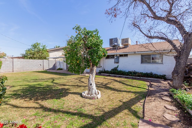 back of house featuring brick siding, central air condition unit, a lawn, and fence