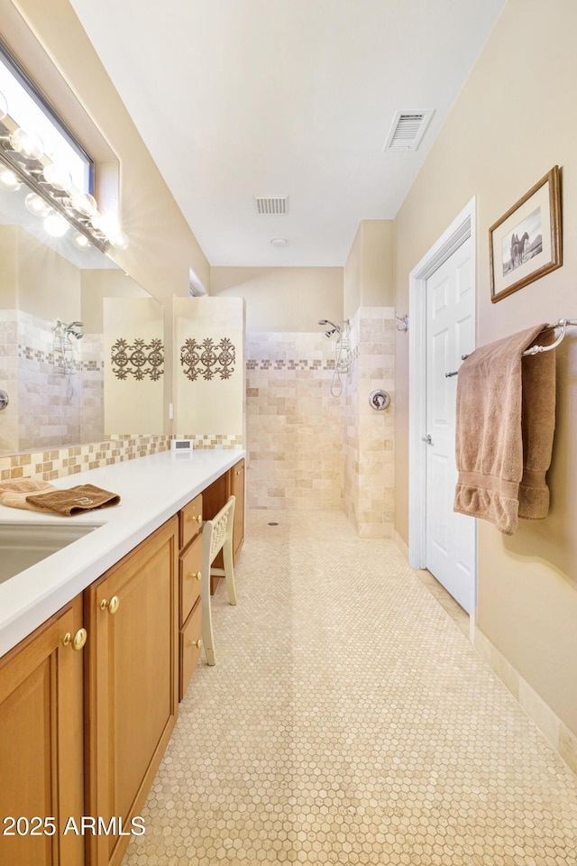 bathroom with tasteful backsplash, visible vents, a walk in shower, and vanity