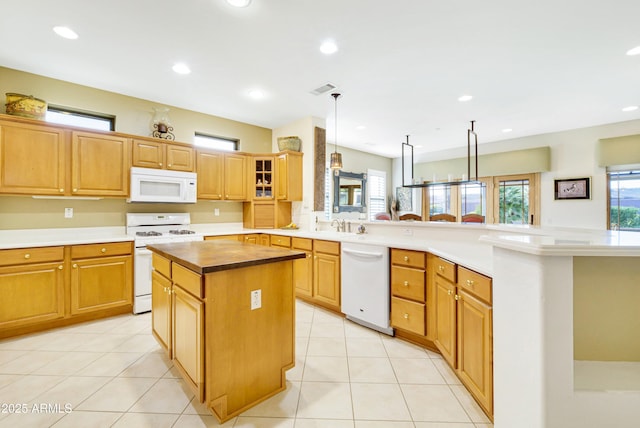 kitchen featuring white appliances, glass insert cabinets, a center island, hanging light fixtures, and a peninsula