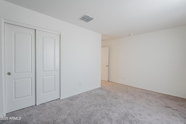 unfurnished bedroom with light colored carpet and a closet