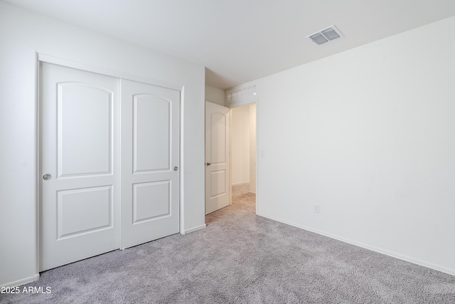 unfurnished bedroom with light carpet and a closet