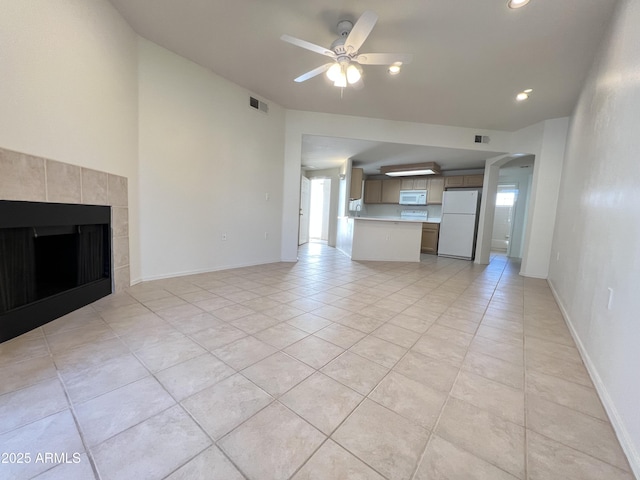 unfurnished living room featuring arched walkways, visible vents, a tiled fireplace, a ceiling fan, and baseboards