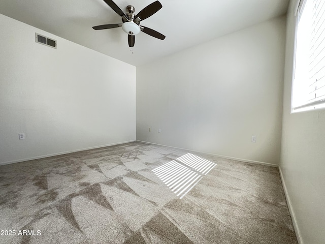 empty room with ceiling fan, carpet floors, visible vents, and baseboards