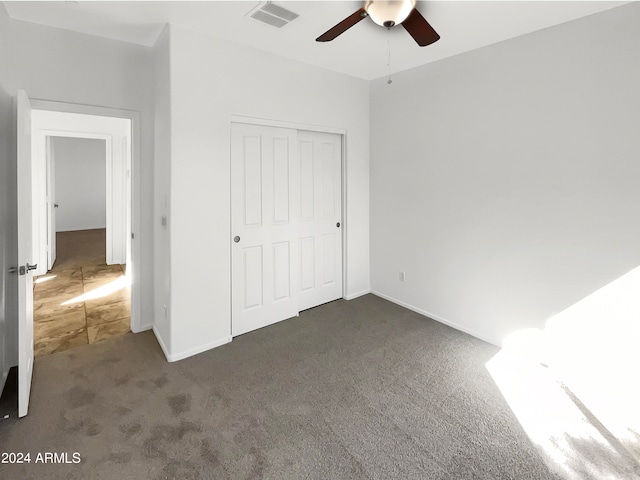 unfurnished bedroom featuring dark carpet, a closet, and ceiling fan