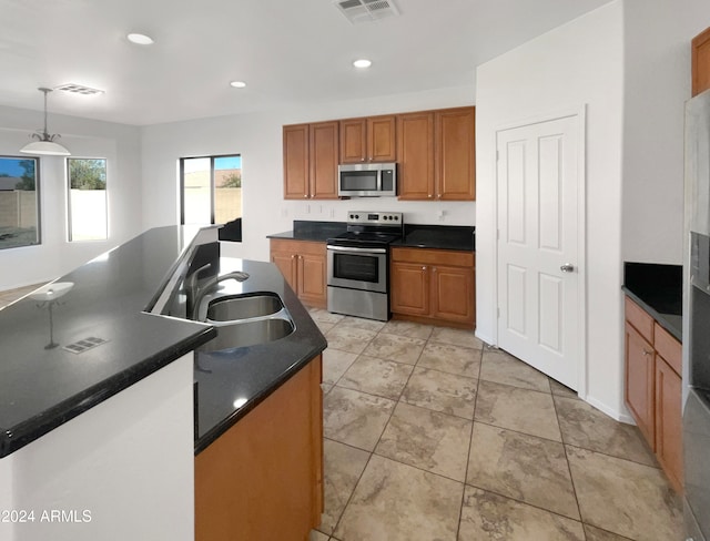 kitchen featuring appliances with stainless steel finishes, decorative light fixtures, and sink