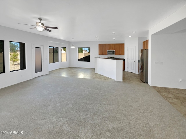 unfurnished living room with light colored carpet and ceiling fan