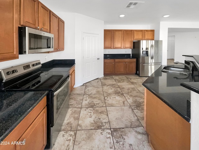 kitchen with dark stone countertops, appliances with stainless steel finishes, and sink