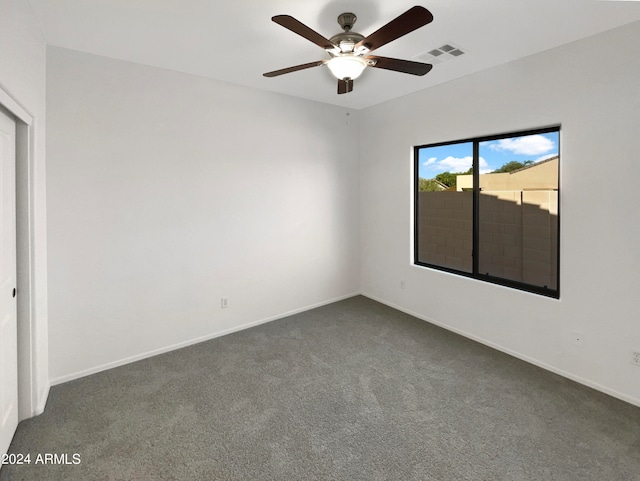 spare room with dark carpet and ceiling fan