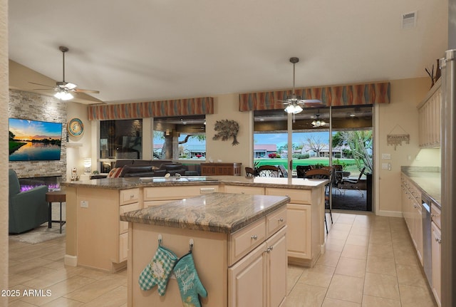 kitchen with light stone countertops, kitchen peninsula, ceiling fan, a center island, and hanging light fixtures