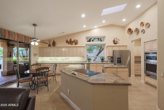 kitchen with a skylight, ceiling fan, a center island, high vaulted ceiling, and appliances with stainless steel finishes