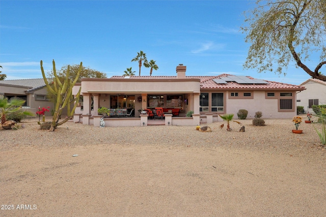 back of property with a patio area and solar panels