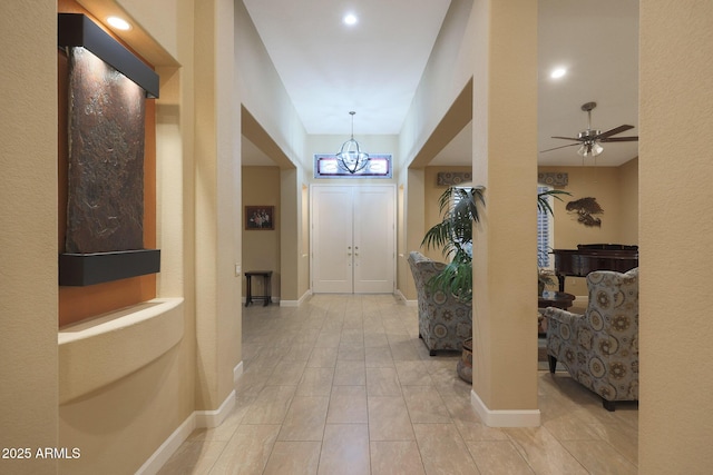 entrance foyer with ceiling fan with notable chandelier