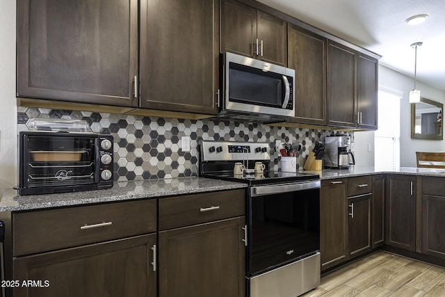 kitchen featuring appliances with stainless steel finishes, pendant lighting, backsplash, and light stone counters