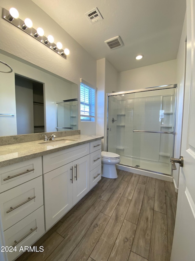 bathroom with vanity, wood-type flooring, toilet, and walk in shower