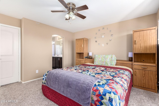 carpeted bedroom with ensuite bath and ceiling fan