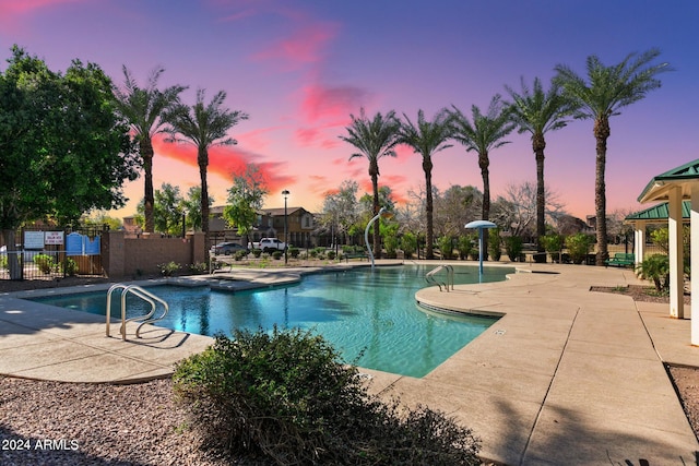 pool at dusk featuring a patio