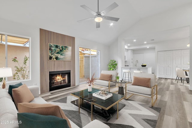 living room with lofted ceiling, sink, ceiling fan, and light hardwood / wood-style flooring