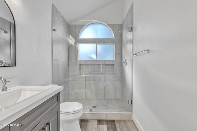 bathroom with toilet, a shower with shower door, vaulted ceiling, vanity, and hardwood / wood-style floors