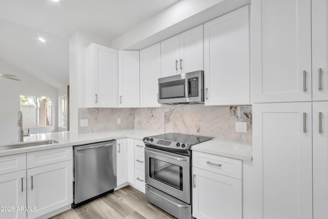 kitchen with stainless steel appliances, sink, white cabinets, and decorative backsplash