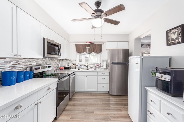 kitchen featuring light wood-type flooring, white cabinetry, appliances with stainless steel finishes, and tasteful backsplash