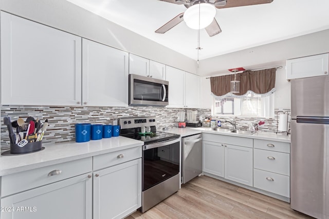 kitchen with backsplash, white cabinets, sink, light hardwood / wood-style floors, and stainless steel appliances