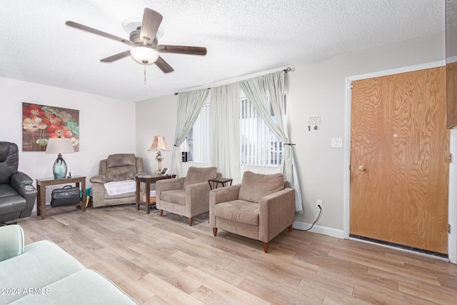 living room featuring ceiling fan, a textured ceiling, and light hardwood / wood-style flooring