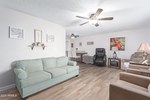 living room featuring ceiling fan, a textured ceiling, and light hardwood / wood-style flooring