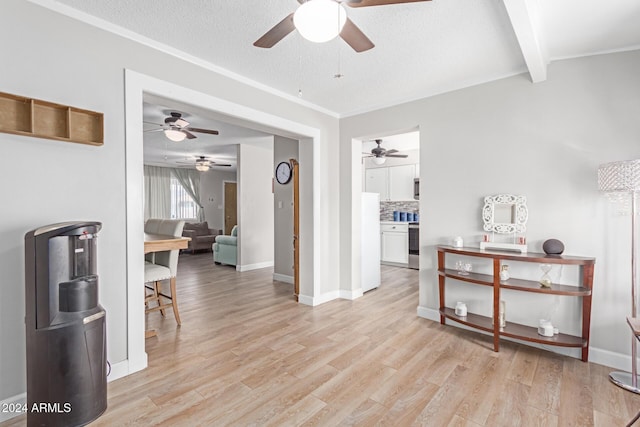 interior space with a textured ceiling, light wood-type flooring, ornamental molding, and beam ceiling