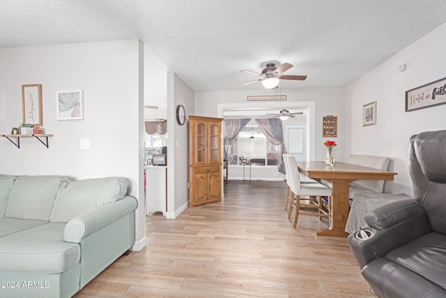 living room featuring a textured ceiling, light wood-type flooring, and ceiling fan