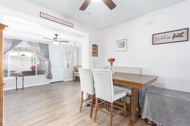 dining area with ceiling fan, light wood-type flooring, and a textured ceiling