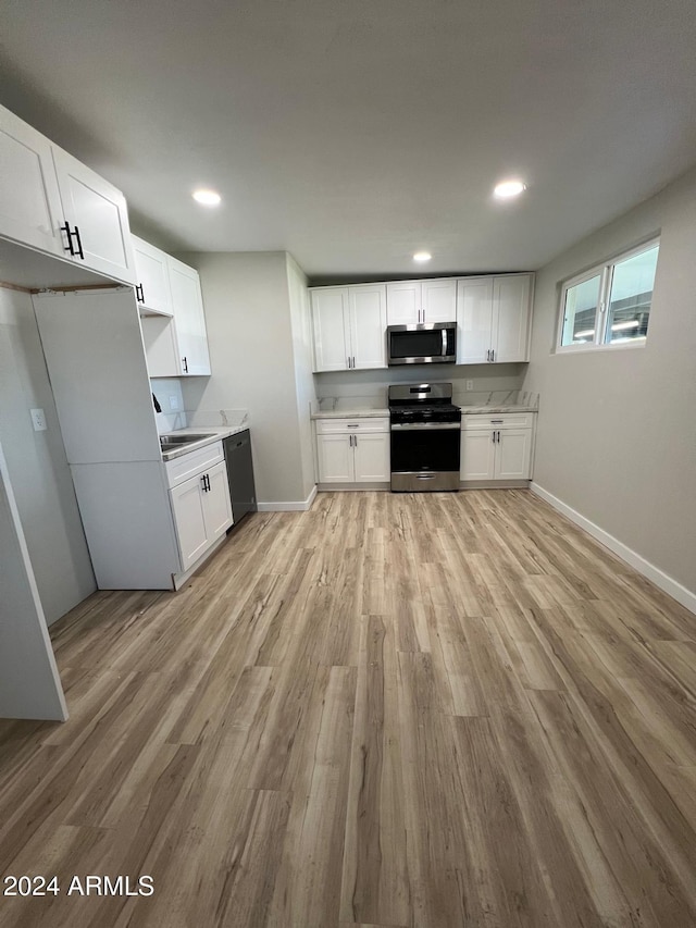 kitchen featuring white cabinets, appliances with stainless steel finishes, and light hardwood / wood-style flooring