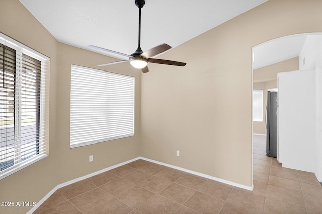 5252 W Pontiac Dr, Glendale, AZ 85308 - unfurnished room with baseboards, vaulted ceiling, light tile patterned floors, a ceiling fan, and arched walkways