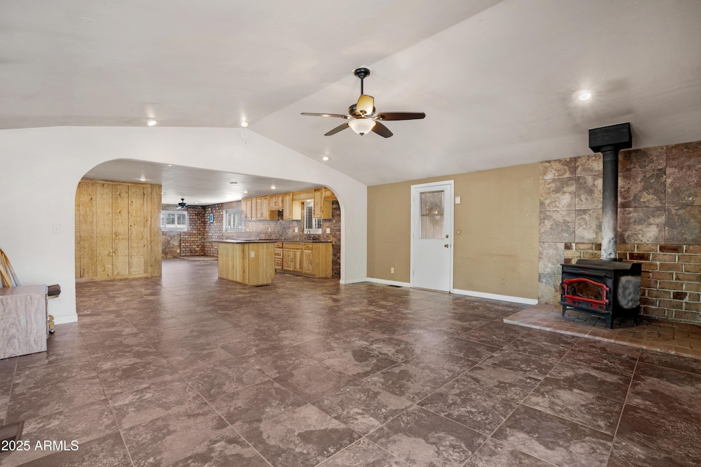 217 W Frontier St, Payson, AZ 85541 - unfurnished living room with arched walkways, lofted ceiling, ceiling fan, baseboards, and a wood stove