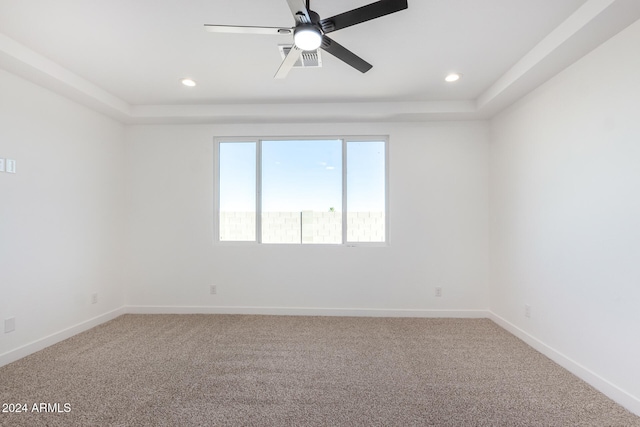 spare room with carpet, ceiling fan, and a raised ceiling