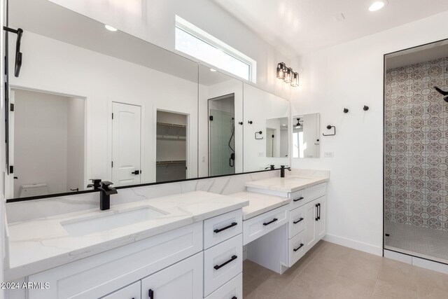 bathroom with walk in shower, vanity, and tile patterned floors