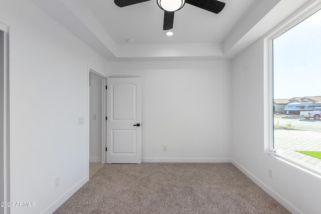 carpeted empty room featuring a tray ceiling and ceiling fan