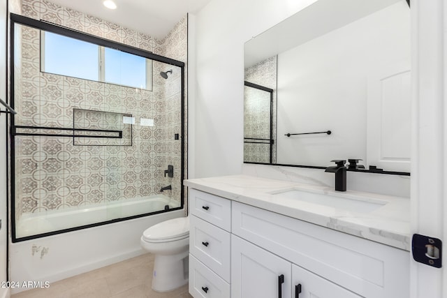 full bathroom with tile patterned flooring, vanity, combined bath / shower with glass door, and toilet