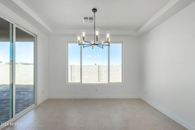 empty room with a tray ceiling and a chandelier