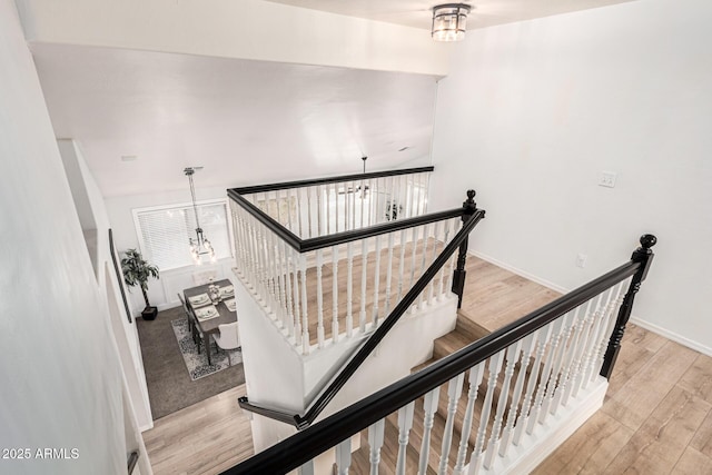 stairway with hardwood / wood-style flooring and a chandelier