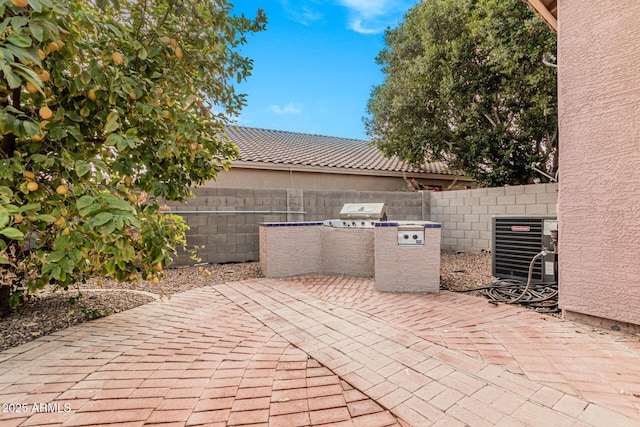 view of patio with central AC unit and exterior kitchen