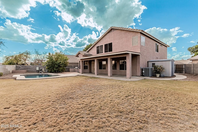 back of property with a pool with hot tub, a patio area, central air condition unit, and a lawn