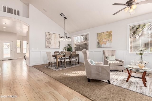 living room featuring ceiling fan with notable chandelier, plenty of natural light, high vaulted ceiling, and light wood-type flooring