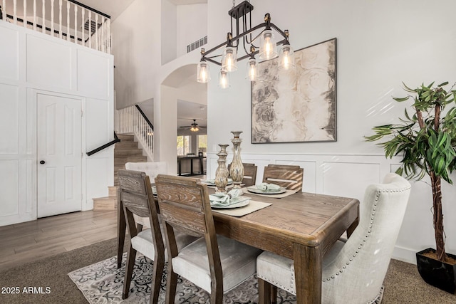 dining area with ceiling fan, a towering ceiling, and hardwood / wood-style floors