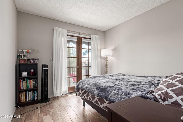 bedroom with baseboards, french doors, a textured ceiling, and wood finished floors