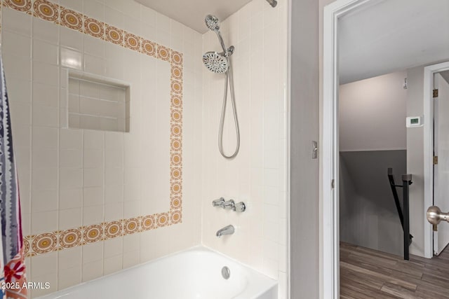bathroom featuring wood finished floors and bathing tub / shower combination