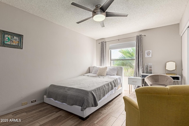 bedroom with a ceiling fan, light wood finished floors, and a textured ceiling