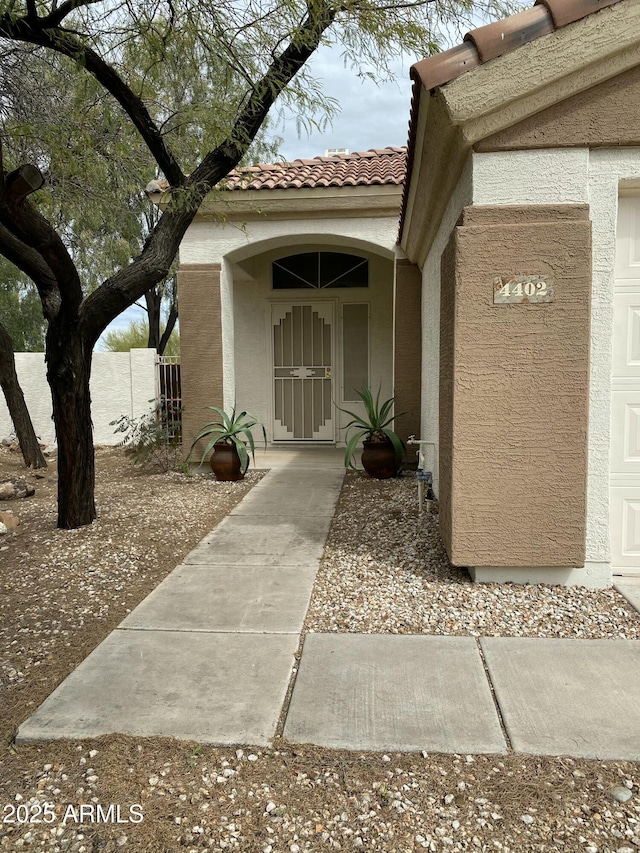 doorway to property featuring stucco siding and a tile roof