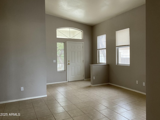 entryway with a wealth of natural light, baseboards, and light tile patterned floors