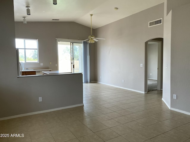 tiled empty room with visible vents, baseboards, ceiling fan, vaulted ceiling, and arched walkways