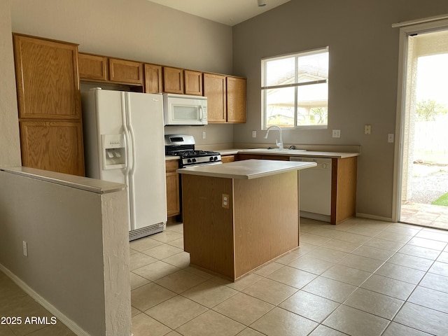 kitchen with a sink, a kitchen island, white appliances, light countertops, and light tile patterned floors
